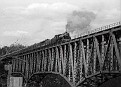 39-Steam engine pulling excursion train full of passengers across high bridge at New River in April 1979.